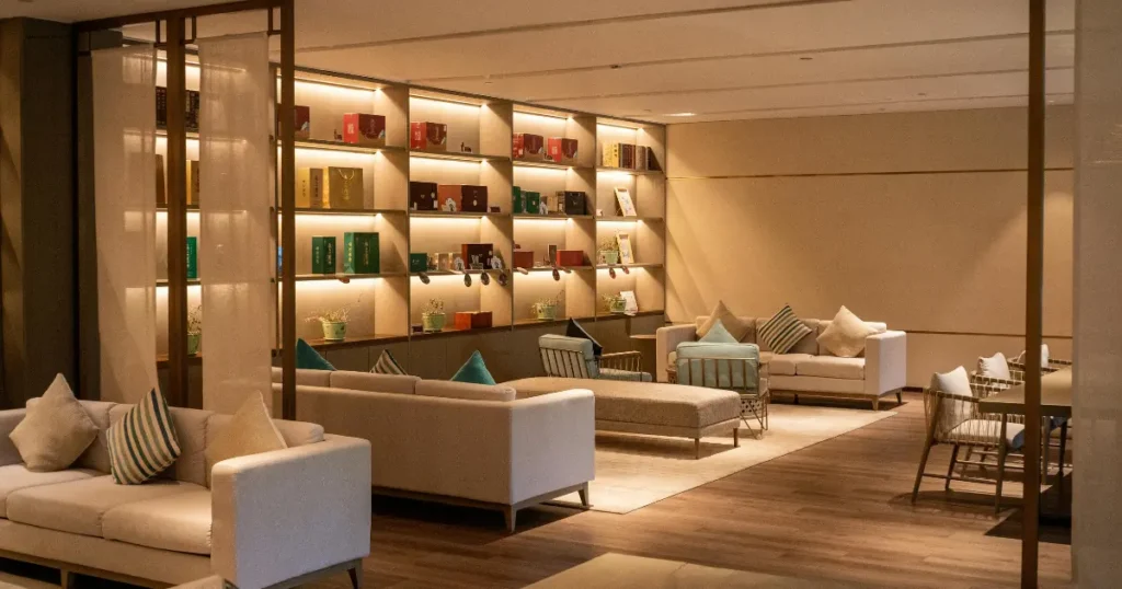 Modern hotel lobby lounge with warm ambient lighting, plush seating, and curated display shelving